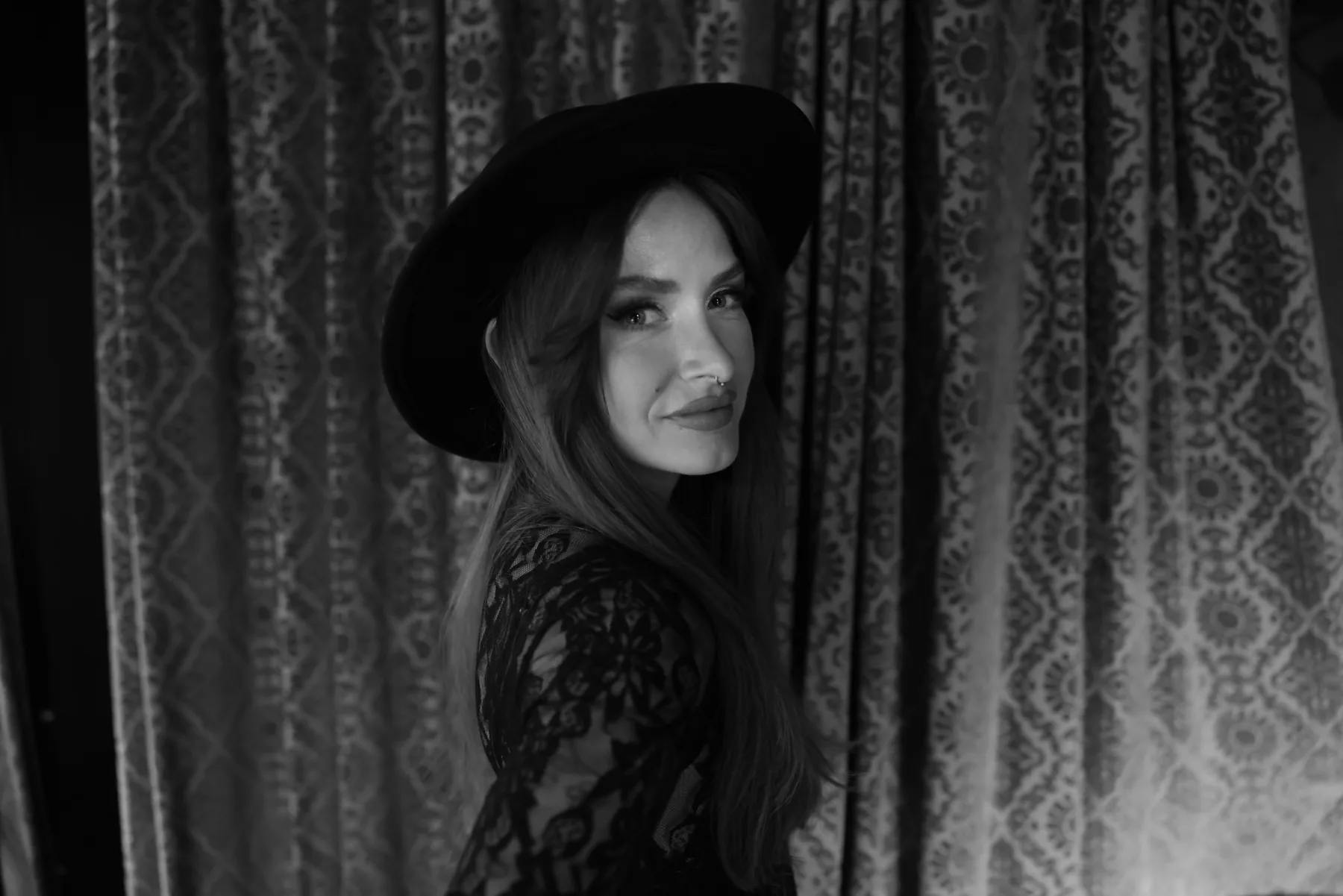 A performer in a wide-brimmed hat against the gold curtain