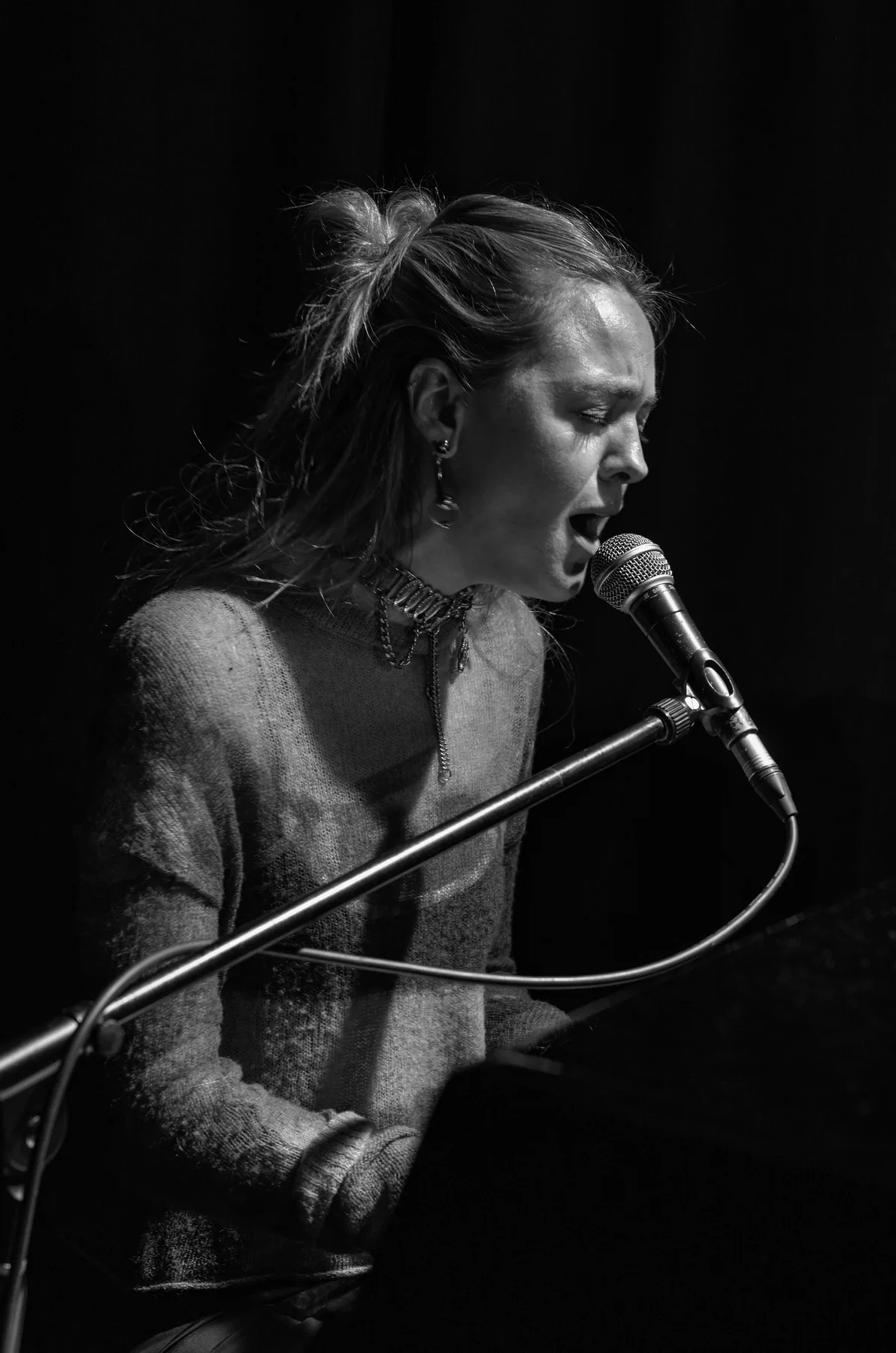 A singer at the piano, caught side-on in the light